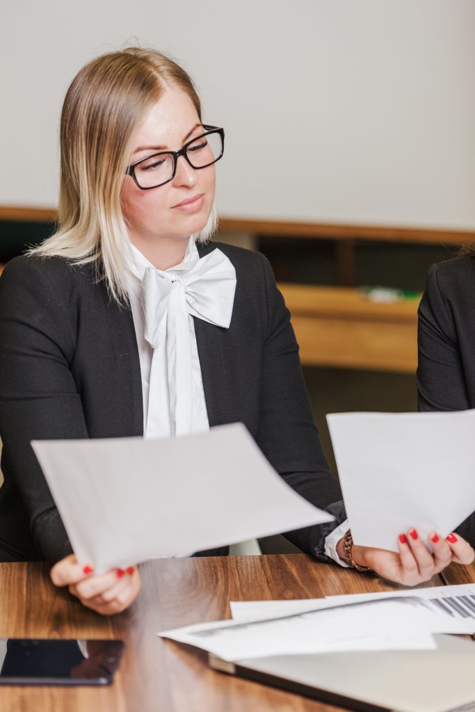 Blonde Woman Sitting Desk Holding Sheets